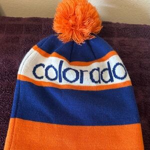 Colorado Unlimited beanie hat with the ball on top of it orange and blue